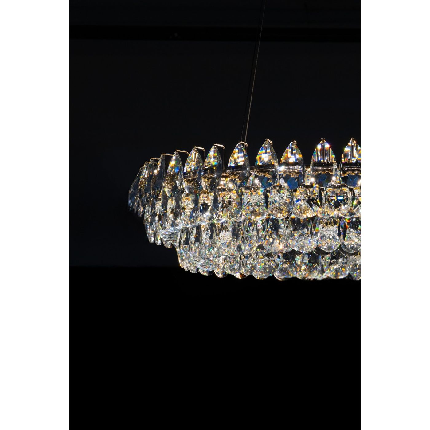 Lampa wisząca Barletta D60+D100 z dwoma źródłami LED o mocy 180W, złota. Ujęcie z boku, ukazujące elegancki, kryształowy klosz z wyraźnymi, połyskującymi detalami w kształcie kropli, zawieszony na cienkim przewodzie. Tło czarne.