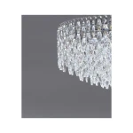 Lampa sufitowa Burano D100 w chromowanej oprawie z kryształowymi elementami, o okrągłym kształcie, z widocznym detalem kryształów w kształcie łez. Ujęcie z boku, na szarym tle, podkreślające przezroczystość i blask materiałów.