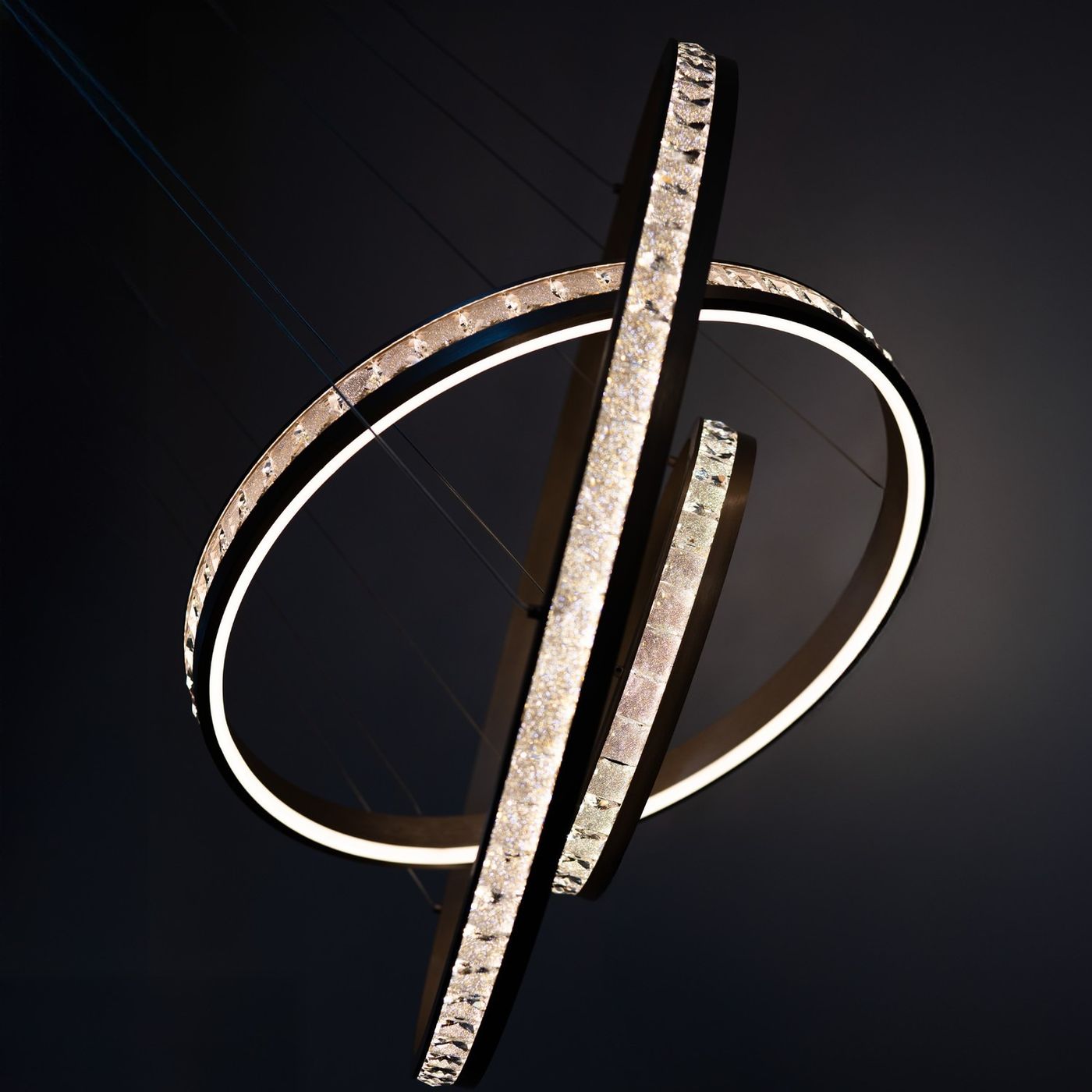 Lampa wisząca Camelia 3xLED 118W w kolorze złotym, składająca się z dwóch okręgów o różnych średnicach, z podświetleniem LED i dekoracyjnymi elementami. Ujęcie z góry, pokazujące detale wykończenia oraz efekt świetlny na ciemnym tle.