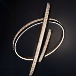 Lampa wisząca Camelia 3xLED 118W w kolorze złotym, składająca się z dwóch okręgów o różnych średnicach, z podświetleniem LED i dekoracyjnymi elementami. Ujęcie z góry, pokazujące detale wykończenia oraz efekt świetlny na ciemnym tle.