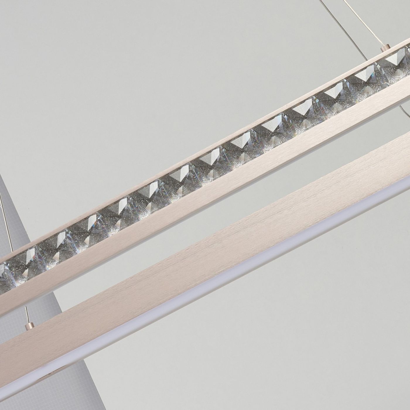 Lampa wisząca Camelia z jedną żarówką LED 60W, w złotym kolorze. Detal z przezroczystymi kryształkami na górnej krawędzi oraz matowym, prostokątnym uchwytem. Ujęcie z góry, ukazujące elegancki design i wykończenie.