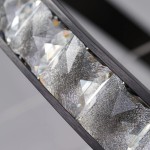 Czarna lampa wisząca Azalea z 1xLED 30W, z bliska ukazująca efektowne, diamentowe wzory kryształowego klosza, który odbija światło. Lampa ma prostą, nowoczesną konstrukcję z metalowym detalem.
