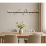 Lampa wisząca Memphis 2xLED 55W w kolorze złotym z falistym designem, zawieszona nad drewnianym stołem. W tle widać wazon z białymi kwiatami oraz szklane naczynia. Prosta, neutralna aranżacja wnętrza.