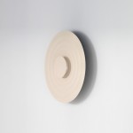 Beżowy kinkiet Ripple D40 z jedną diodą LED 6W, o okrągłej, falistej strukturze, zamontowany na ścianie. Produkt w kolorze jasnego beżu, z centralnym okrągłym elementem. Tło jasne, minimalistyczne.
