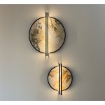 Kinkiet LED Saturn 20W w kolorze czarnym, z dwoma okrągłymi kloszami o marmurkowej fakturze w odcieniach beżu i złota. Zamontowany na ścianie, z delikatnym podświetleniem, tworzy nowoczesny efekt świetlny.