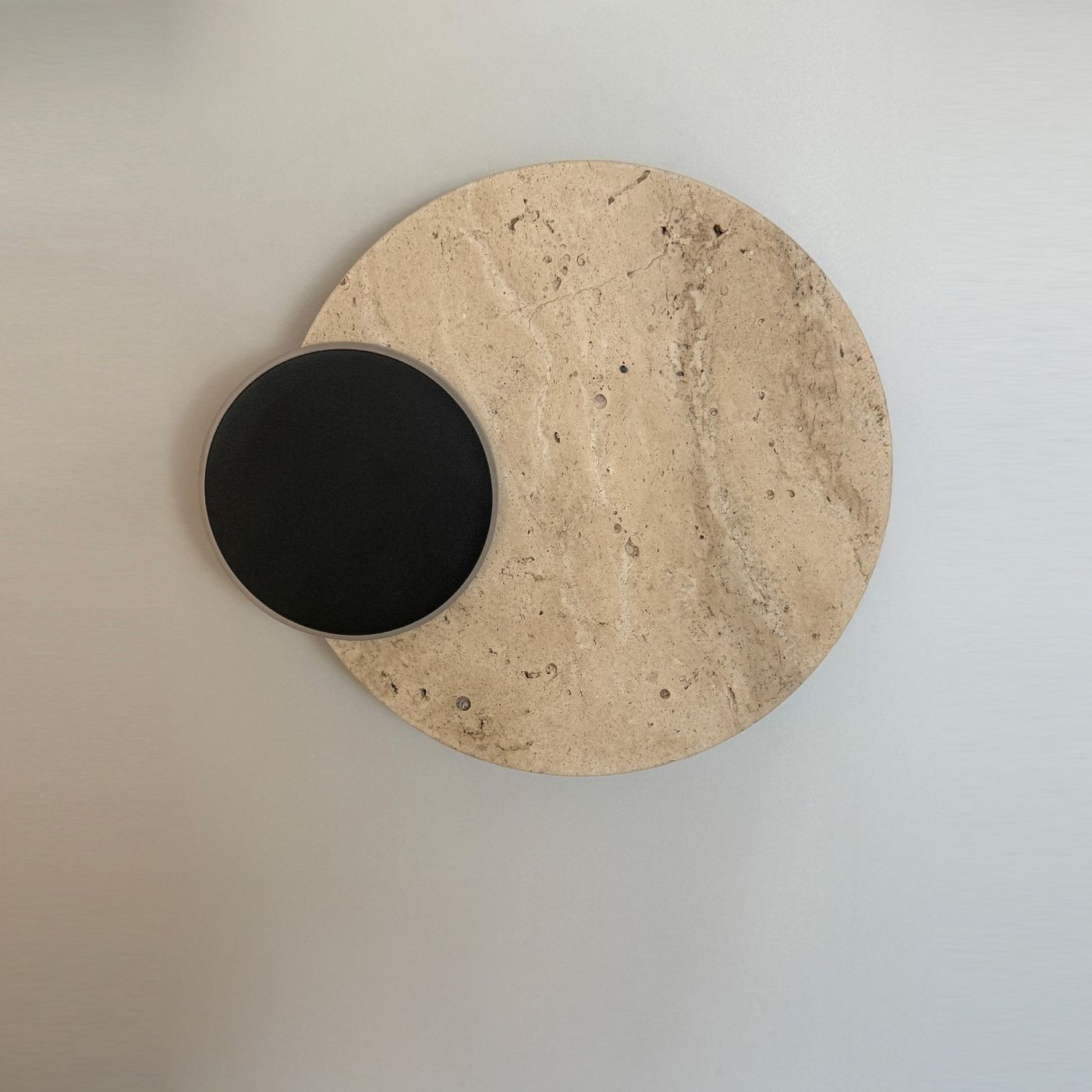 Kinkiet Eclipse 2xLED 14W w kolorze czarnym, montowany na ścianie. Okrągła baza z jasnego kamienia naturalnego z małym, czarnym okręgiem. Prosty, nowoczesny design, idealny do stylowych wnętrz.