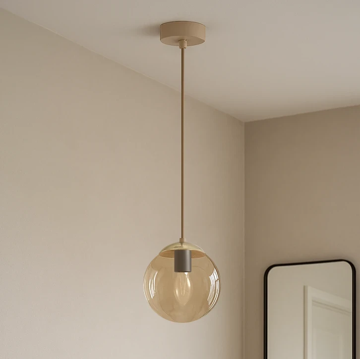 Lampa wisząca Felix 1xE14 w kolorze beżowym z bursztynowym, szklanym kloszem w kształcie kuli, zawieszona na cienkim kablu. Widoczne okrągłe, metalowe mocowanie sufitowe. Tło jasne, neutralne.