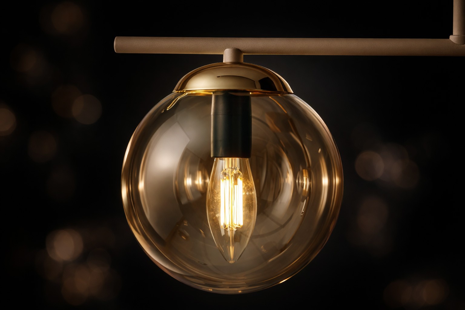 Beżowa lampa sufitowa Felix z bursztynowym kloszem, zawieszona na metalowej konstrukcji. Widoczna żarówka E14 w kształcie łzy. Klosz ma okrągły, przezroczysty kształt, co podkreśla elegancję produktu. Tło ciemne, skupiające uwagę na lampie.