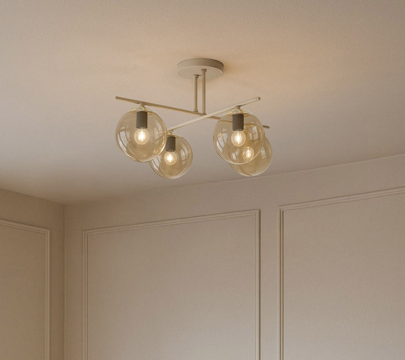 Lampa sufitowa Felix z czterema miejscami na żarówki E14, beżowa z bursztynowymi kloszami, zamontowana na prostym, metalowym stelażu. Klosze mają okrągły kształt, a całość znajduje się na jasnym tle.