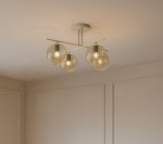 Lampa sufitowa Felix z czterema miejscami na żarówki E14, beżowa z bursztynowymi kloszami, zamontowana na prostym, metalowym stelażu. Klosze mają okrągły kształt, a całość znajduje się na jasnym tle.