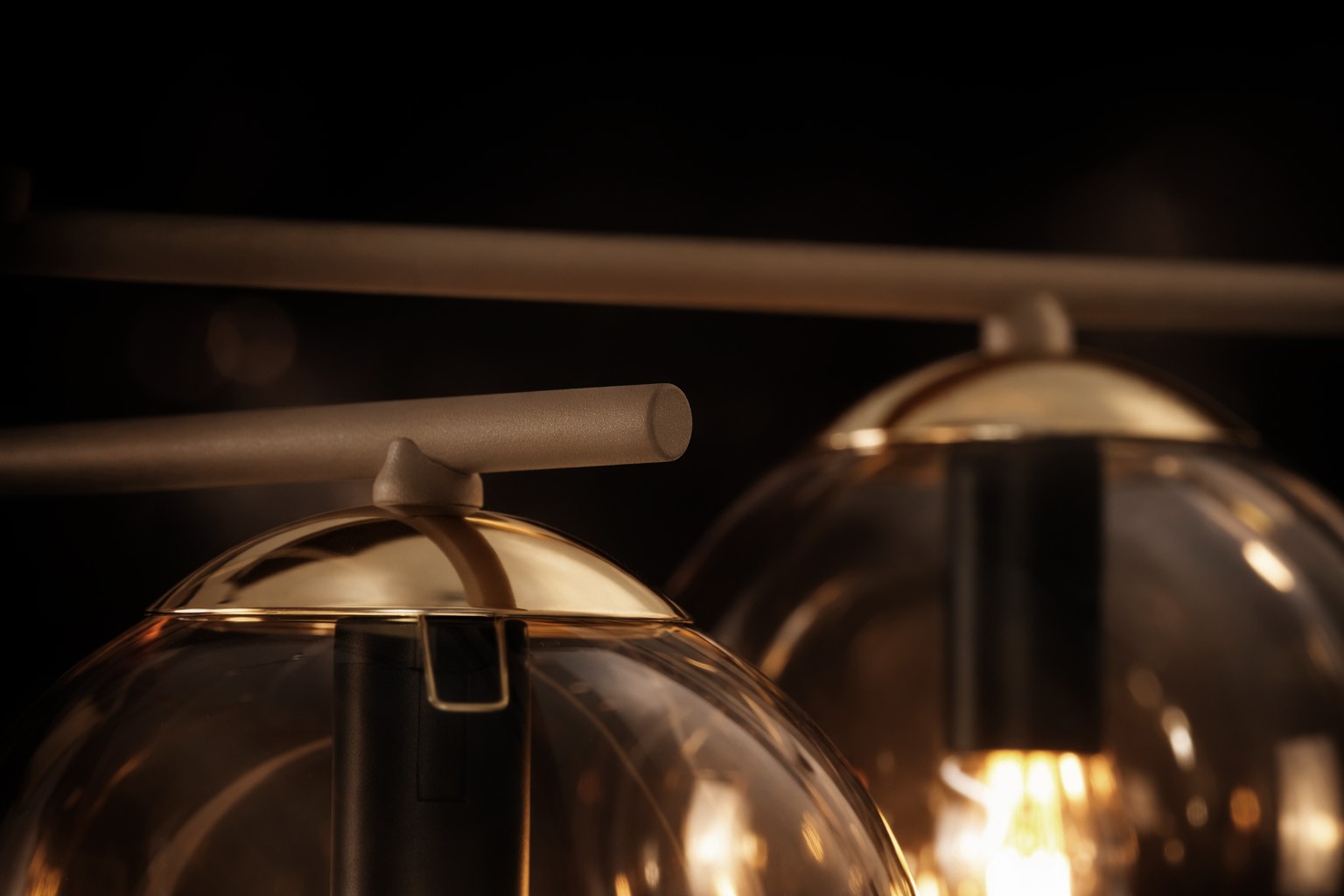 Lampa sufitowa Felix z sześcioma oprawami E14, beżowa z bursztynowymi kloszami. Ujęcie z bliska, pokazujące detale złotych wykończeń i matowej konstrukcji. Klosze w kształcie półkul, zamontowane na poziomej listwie.