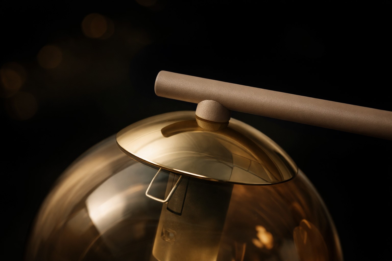 Kinkiet Felix w kolorze beżowym z bursztynową, półprzezroczystą kloszem. Zbliżenie na górną część lampy, z prostą, matową rurką montażową. Widoczny detal elementu mocującego oraz subtelny połysk klosza. Tło ciemne, podkreślające elegancję lampy.