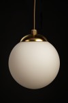 Lampa wisząca Savia z kloszem w kształcie kuli, wykonana z matowego szkła w kolorze białym, z metalowym, złotym wykończeniem u góry. Zawieszona na cienkim przewodzie, widoczna z przodu na ciemnym tle.