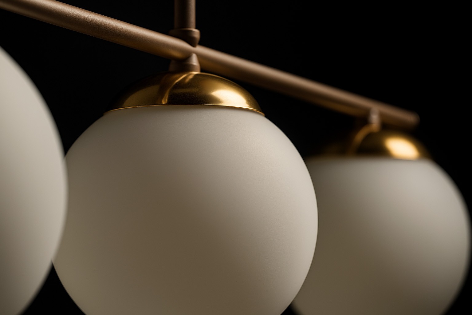 Beżowa lampa sufitowa Savia z trzema okrągłymi kloszami w białym kolorze, zawieszona na metalowym stelażu w kolorze złotym. Zbliżenie na detale kloszy i mocowania, ukazujące matową fakturę szkła.