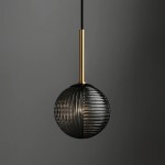 Lampa wisząca Fado, 1xG9, o okrągłym kloszu w czarnym i grafitowym kolorze, z fakturą żeberkową. Metalowy uchwyt w kolorze złotym. Zawieszona na cienkim kablu, w zbliżeniu na detal klosza. Tło szare.
