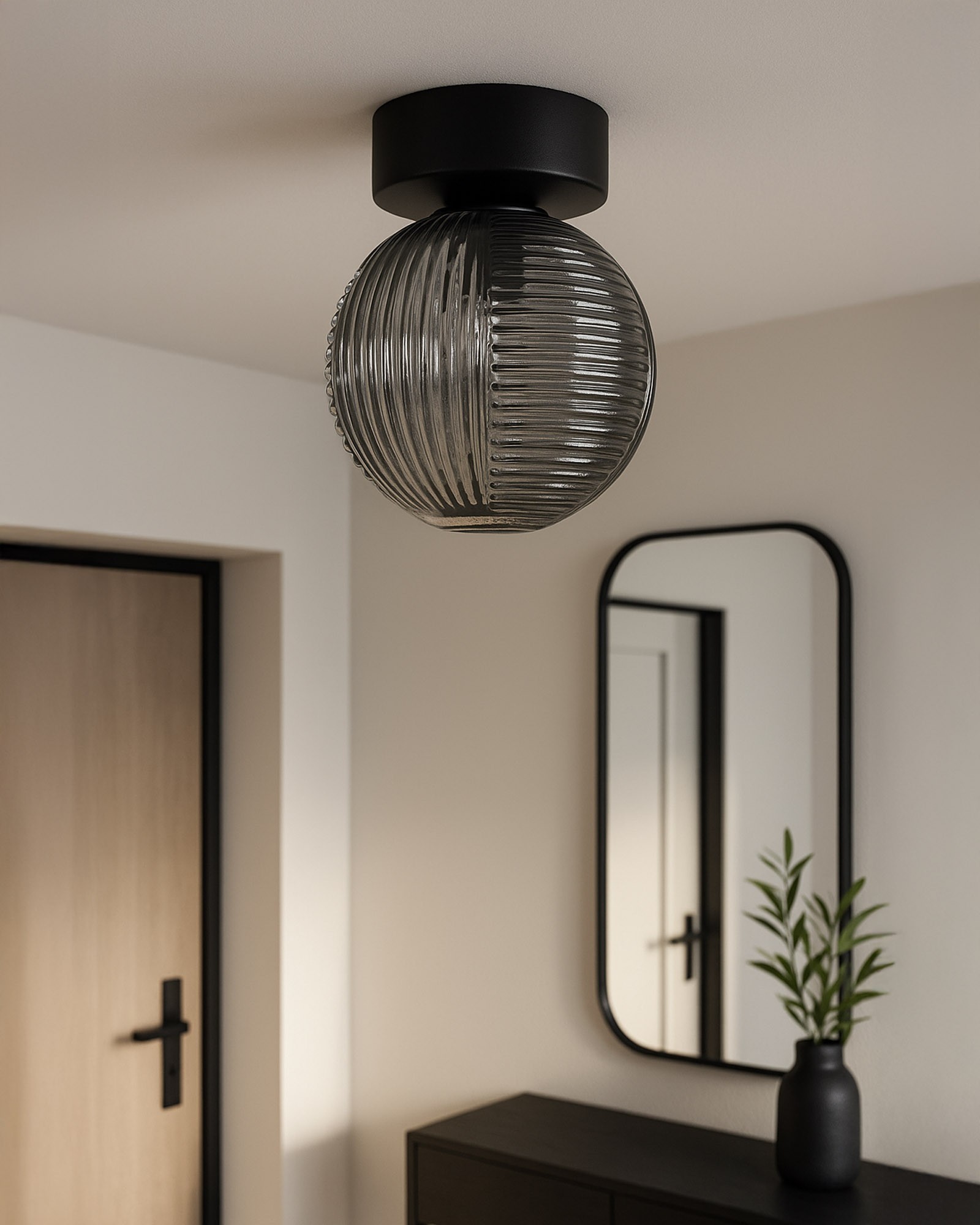 Lampa sufitowa Fado z czarnym metalowym mocowaniem oraz szklanym kloszem w odcieniu grafitowym, o okrągłym kształcie z żłobieniami. Zawieszona na suficie, w tle widoczna szafka i lustro. Idealna do nowoczesnych wnętrz.