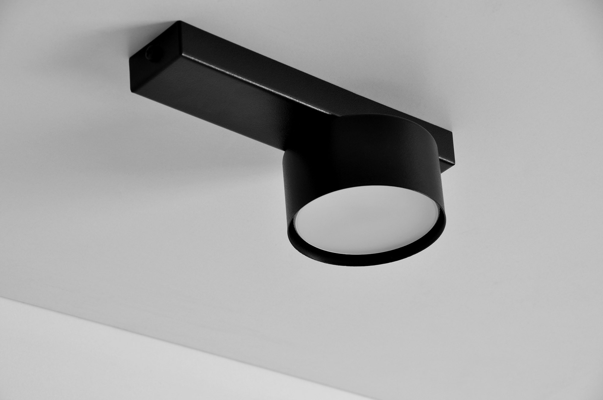 Cruz lampa sufitowa 1xGX53 w kolorze czarnym, o okrągłej głowicy z matowym szkłem, zamontowana na prostokątnej podstawie. Widok z dołu, podkreślający minimalistyczny design i jednolite tło.