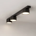 Cruz lampa sufitowa w kolorze czarnym z trzema okrągłymi oprawami na żarówki GX53. Montowana na suficie, o prostym, nowoczesnym designie. Widać gładką powierzchnię i delikatne wykończenie ramy.