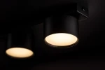 Cruz lampa sufitowa 4xGX53 w kolorze czarnym, z okrągłymi, matowymi kloszami emitującymi ciepłe światło. Ujęcie z boku, pokazujące dwa klosze zamontowane na prostokątnej podstawie. Tło ciemne, minimalistyczne.
