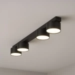 Cruz lampa sufitowa czarna z czterema okrągłymi kloszami GX53, zamontowana na prostokątnej podstawie. Klosze emitują ciepłe światło, umieszczone równolegle na jednolitym tle. Idealna do nowoczesnych wnętrz.