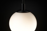 Lampa wisząca Aspen 1xG9 w kolorze czarnym i białym. Okrągła, matowa kula z białego szkła, zawieszona na czarnym, metalowym mocowaniu. Ujęcie z góry, na jednolitym tle.