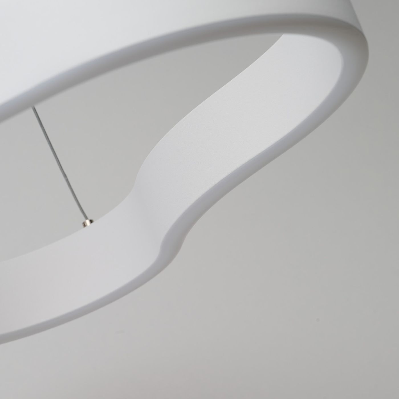 Biała lampa wisząca LED Mirabella 90 o mocy 48W, widok zbliżeniowy na górną część klosza o gładkiej, matowej fakturze. Lampa ma nowoczesny, zaokrąglony kształt, zawieszona na cienkim drucie. Tło jasnoszare, co podkreśla elegancję produktu.