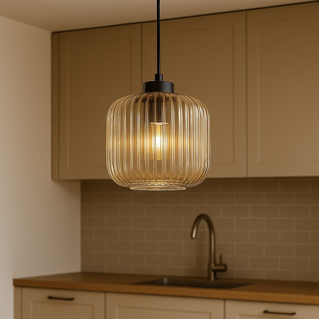 Lampa wisząca Clark D20 z czarnym metalowym mocowaniem i bursztynowym, żebrowanym kloszem, zawieszona w kuchni nad blatem. Oświetlenie E27 emituje ciepłe światło, tworząc przytulną atmosferę. Tło w jasnych odcieniach.