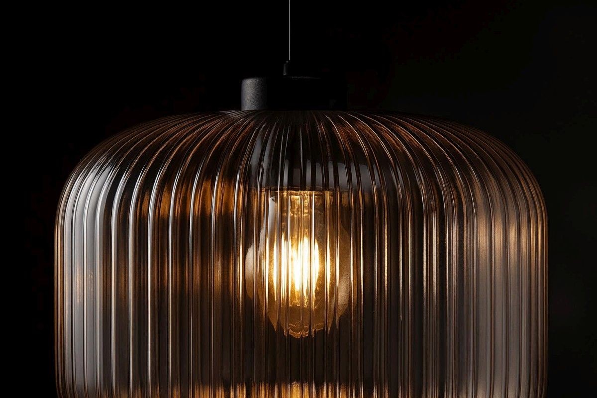 Lampa wisząca Clark D30 z kloszem w kolorze czarnym i bursztynowym, z wyraźnymi pionowymi żłobieniami. Zawiera źródło światła E27, podwieszona na cienkim, czarnym przewodzie. Klosz ma owalny kształt, a w środku widoczna żarówka, emitująca ciepłe światło.