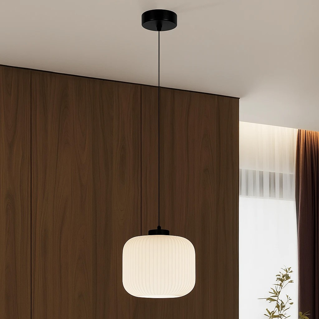 Lampa wisząca Sparta D20 z oprawą w kolorze czarnym i kloszem w białym, o kształcie prostokątnym z żłobieniami, zawieszona na cienkim przewodzie, umieszczona w jasnym wnętrzu z drewnianą ścianą w tle.