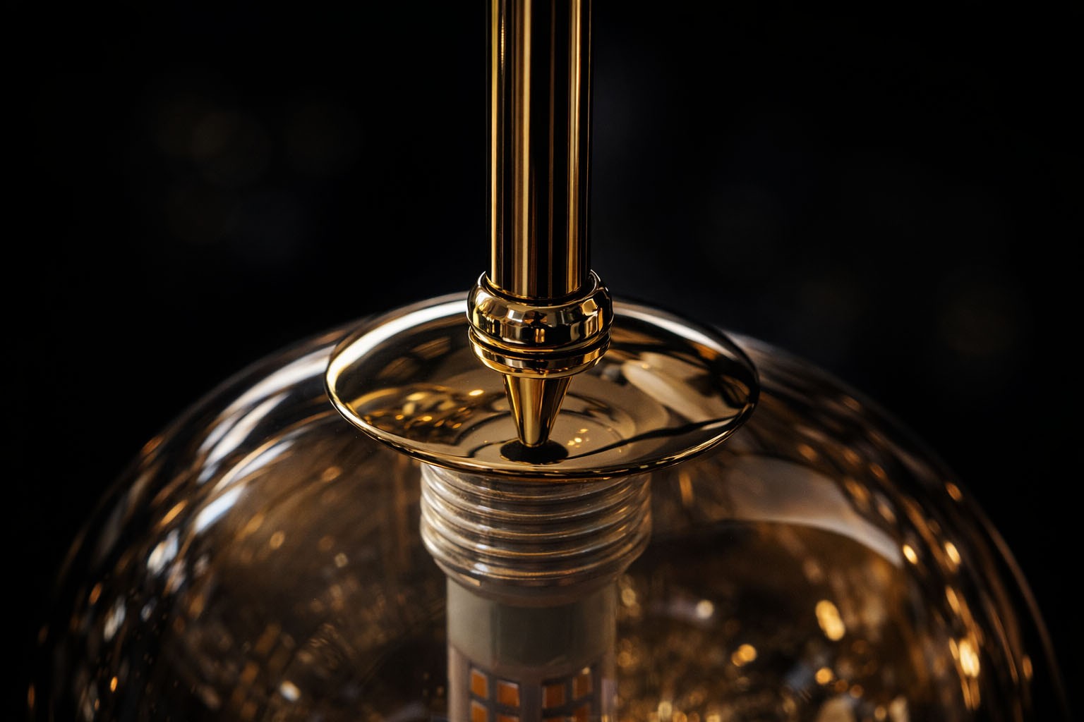 Lampa wisząca Galaxy w kolorze czarnym z bursztynowym kloszem, z elementami metalowymi w złotym wykończeniu. Ujęcie z góry ukazuje detal mocowania oraz wewnętrzną strukturę lampy. Wysoka jakość wykonania i elegancki design.