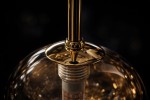 Lampa wisząca Galaxy w kolorze czarnym z bursztynowym kloszem, z elementami metalowymi w złotym wykończeniu. Ujęcie z góry ukazuje detal mocowania oraz wewnętrzną strukturę lampy. Wysoka jakość wykonania i elegancki design.