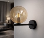 Kinkiet Galaxy z czarnym metalowym uchwytem i bursztynową, szklaną kulą. Oświetlenie montowane na ścianie, prezentujące stylowy design. Kula z widoczną żarówką wewnątrz, umieszczona na poziomej belce. Tło w stonowanej aranżacji wnętrza.