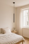 Lampa wisząca Gelato 1xG9 w kolorze czarnym, o prostokątnym kształcie, zawieszona na długim przewodzie w minimalistycznym wnętrzu sypialni. Obok widoczna drewniana szafka nocna z wazonem i rośliną.