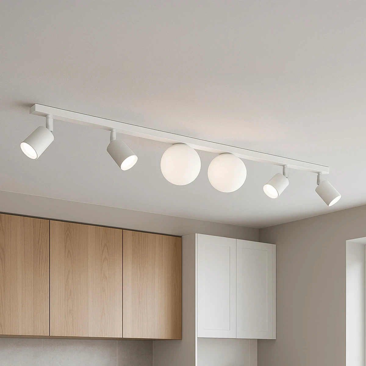 Lampa sufitowa Andi z białym wykończeniem, składająca się z czterech reflektorów GU10 i dwóch kul G9. Ujęcie z góry, pokazujące lampę zamontowaną na prostej listwie w nowoczesnym wnętrzu. W tle drewniane i białe szafki.