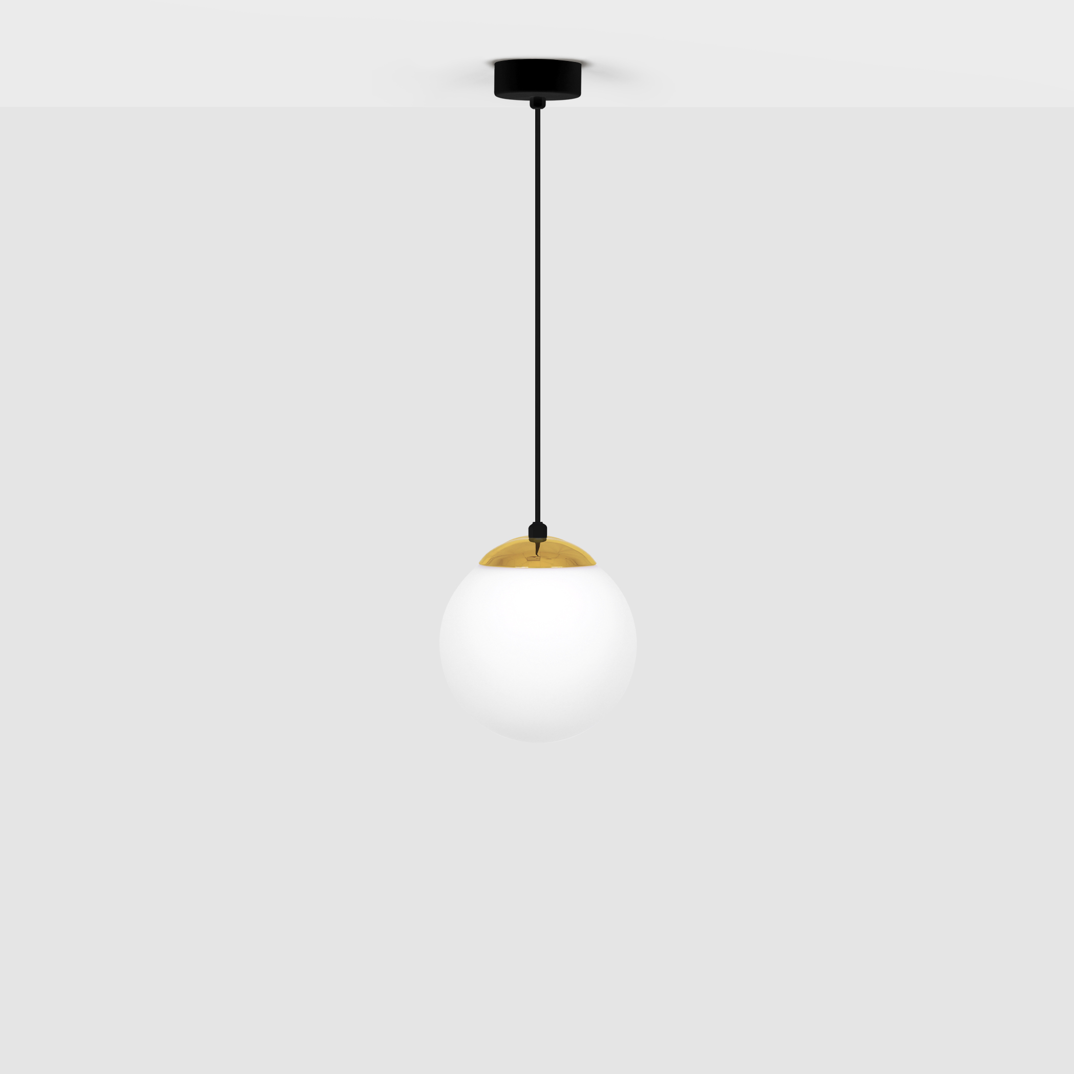 Lampa wisząca Isla D16, 1-punktowa, z czarnym przewodem i okrągłym kloszem z białego szkła, zdobiona mosiężnym detalem u góry. Zawieszona na czarnej podsufitce, w prostym otoczeniu na jasnym tle.