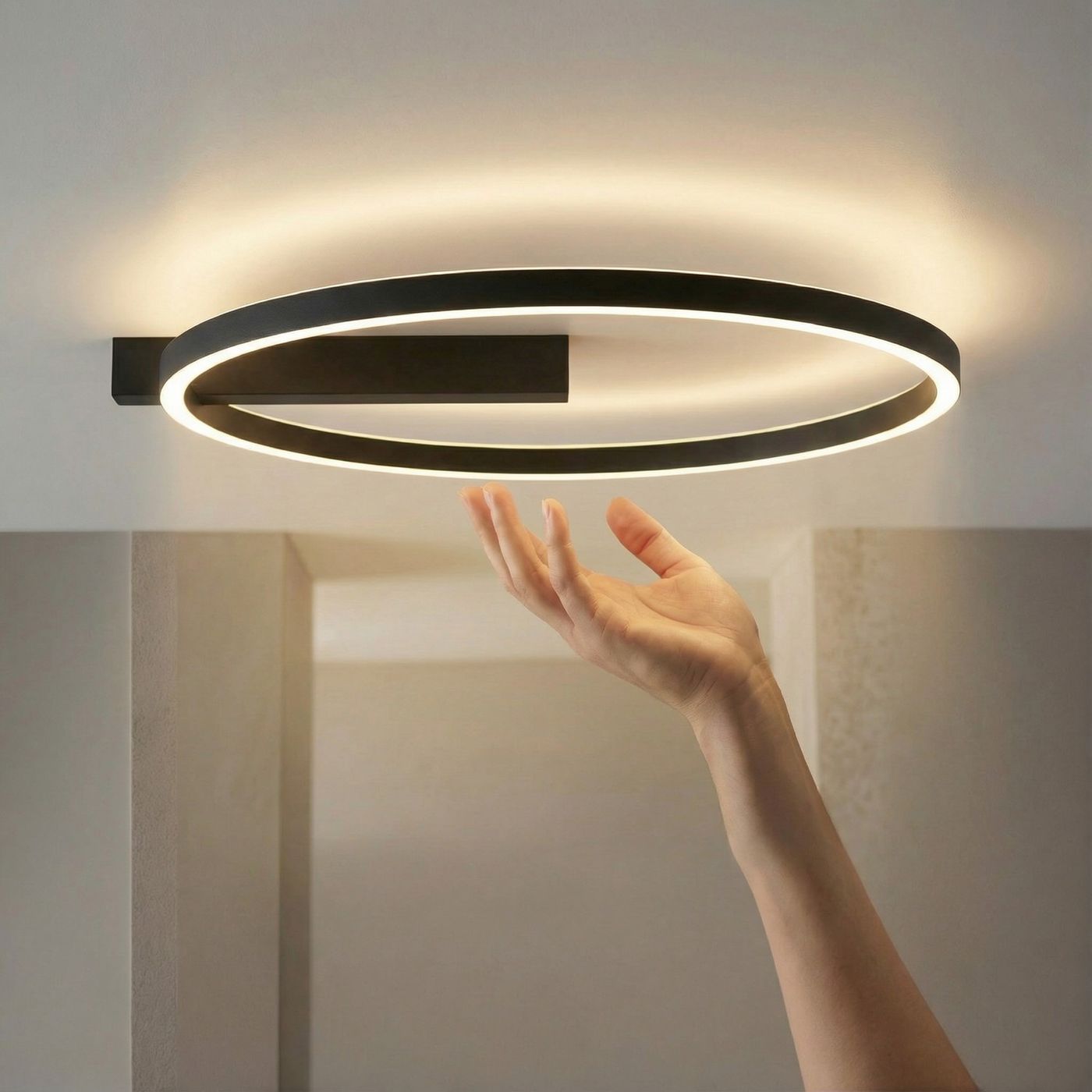 Czarna lampa sufitowa Arte z dwoma źródłami LED o mocy 30W, w kształcie okręgu. Zawieszona na ścianie, emituje ciepłe światło. Widoczna ręka zbliżająca się do lampy, co sugeruje jej użytkowanie. Tło w neutralnych odcieniach.