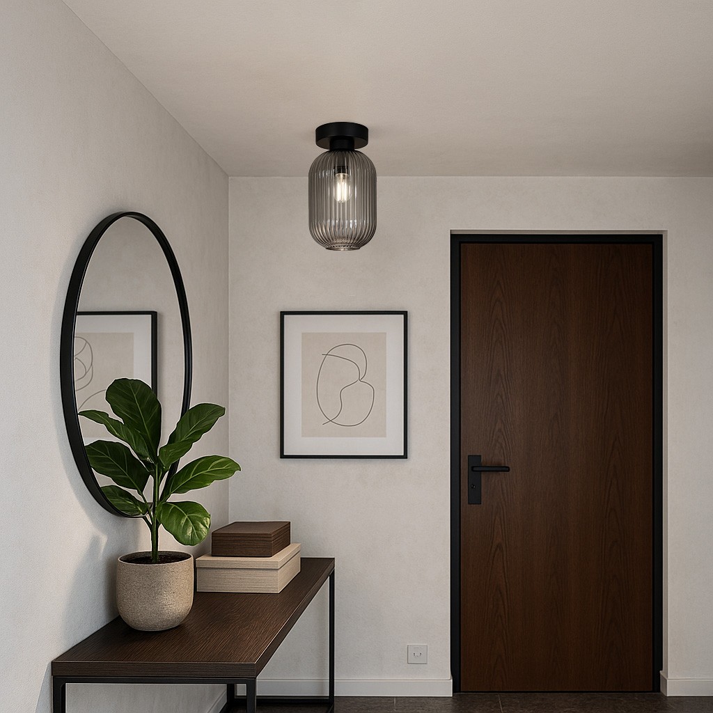 Lampa sufitowa Silva 1xE27 w kolorze czarnym i grafitowym, zamontowana na suficie, ma szklany klosz z pionowymi żłobieniami. W tle widoczna drewniana komoda z rośliną doniczkową oraz lustro w okrągłej ramie.