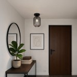 Lampa sufitowa Silva 1xE27 w kolorze czarnym i grafitowym, zamontowana na suficie, ma szklany klosz z pionowymi żłobieniami. W tle widoczna drewniana komoda z rośliną doniczkową oraz lustro w okrągłej ramie.