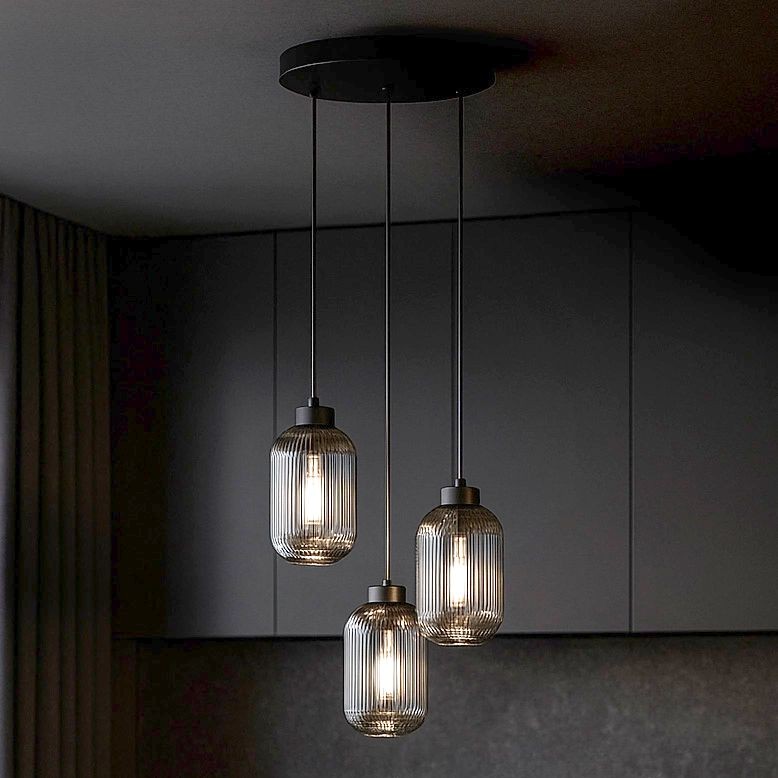 Lampa wisząca Silva 3xE27 w kolorze czarnym i grafitowym, z trzema szklanymi kloszami o żłobionej fakturze, zawieszona na metalowych linkach. Ujęcie z góry, w minimalistycznym wnętrzu, na tle ciemnej zabudowy.