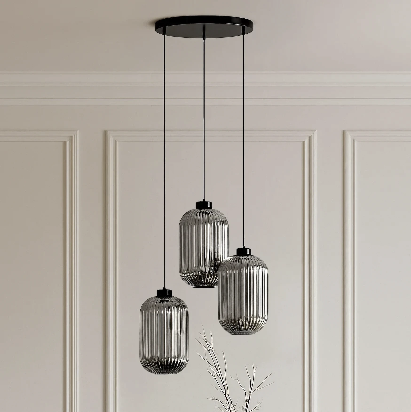 Lampa wisząca Silva z trzema kloszami E27 w kolorze czarnym i grafitowym. Klosze mają pionowe żłobienia, zawieszone na cienkich, czarnych linkach. Ujęcie frontalne, lampa wisi z sufitu na gładkiej, jasnej ścianie.