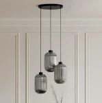 Lampa wisząca Silva z trzema kloszami E27 w kolorze czarnym i grafitowym. Klosze mają pionowe żłobienia, zawieszone na cienkich, czarnych linkach. Ujęcie frontalne, lampa wisi z sufitu na gładkiej, jasnej ścianie.