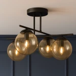 Lampa sufitowa Delta z czarnym stelażem, wyposażona w cztery bursztynowe kuliste klosze. Ujęcie z dołu, ukazujące kształt i detale kloszy oraz mocowania. Lampa idealna do nowoczesnych wnętrz.