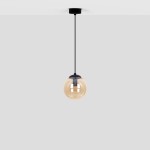 Lampa wisząca Delta z jedną oprawą E14, w kolorze czarnym z bursztynowym kloszem, zawieszona na cienkim czarnym przewodzie. Klosz ma okrągły kształt, przezroczysty, z połyskującą powierzchnią. Montaż sufitowy, na jednolitym, jasnoszarym tle.
