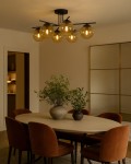 Lampa sufitowa Delta z sześcioma kloszami E14 w kolorze czarnym i bursztynowym, zamontowana na suficie. Klosze w kształcie kul, z widocznymi żarówkami, w otoczeniu jadalni z okrągłym stołem i krzesłami w odcieniu brązowym.