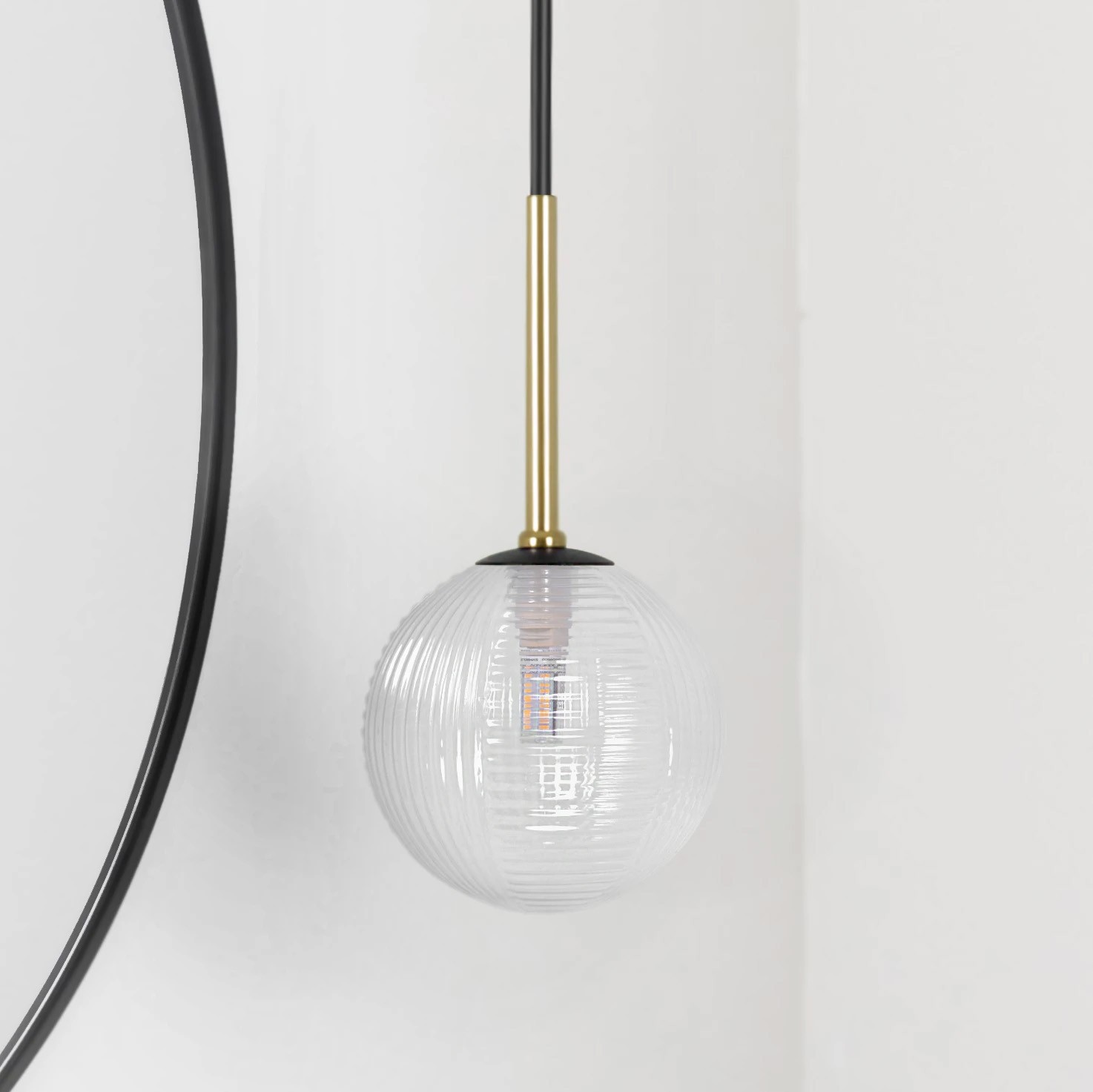 Czarna lampa wisząca Aura z przezroczystym kloszem, o okrągłym kształcie z fakturą. Zawieszona na cienkim kablu, z metalowym elementem w kolorze złota. Idealna do nowoczesnych wnętrz.