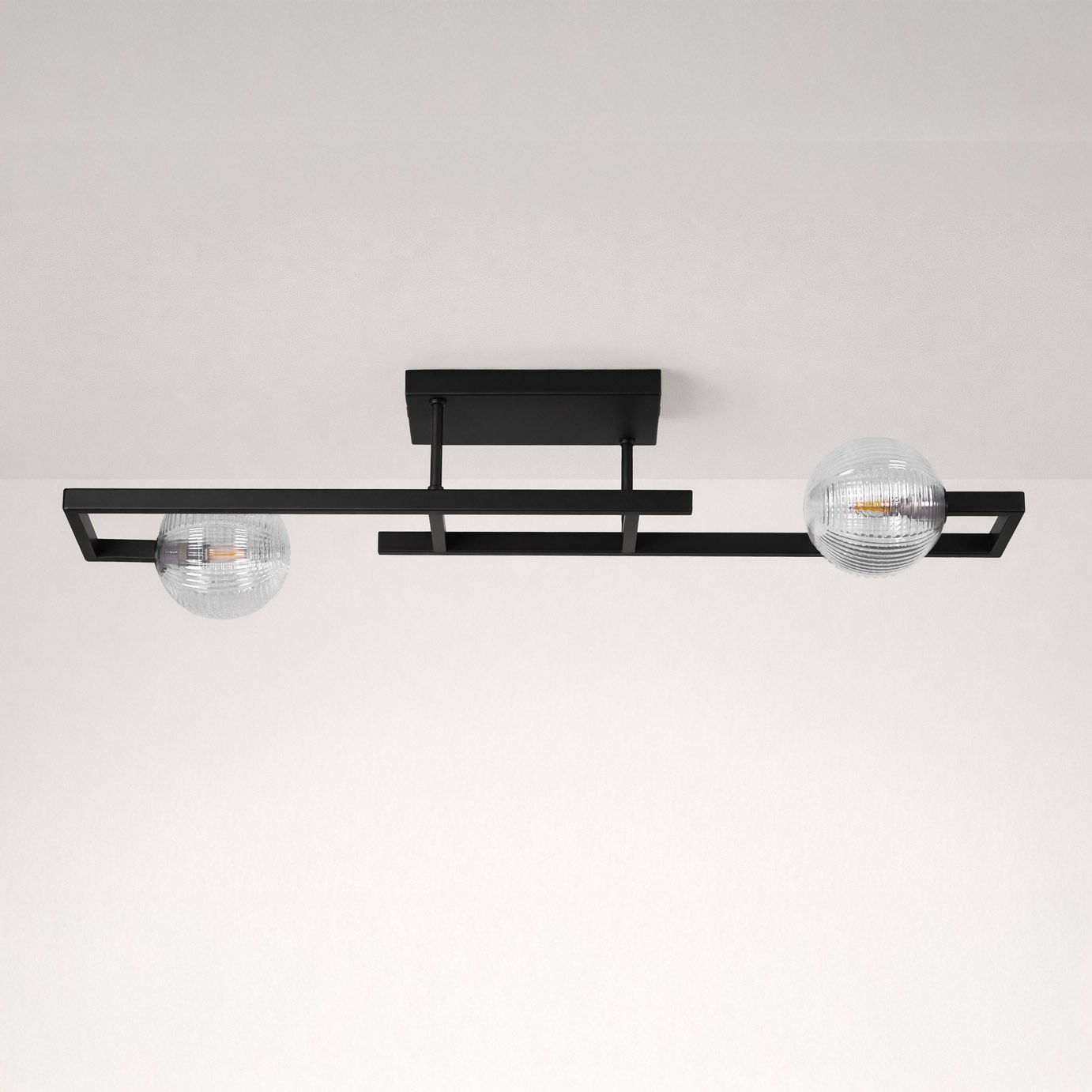 Lampa sufitowa Parma 2xG9 w kolorze czarnym z przezroczystymi kloszami, zamontowana na prostokątnej podstawie. Ujęcie z góry, ukazujące dwa szklane klosze o teksturowanej powierzchni. Tło jasne, jednolite.