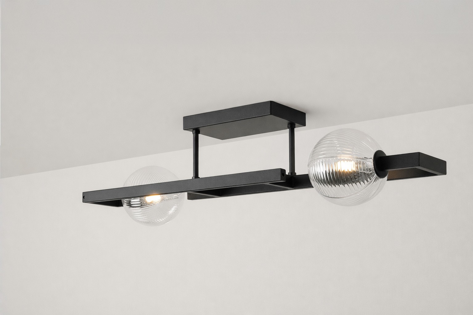 Lampa sufitowa Parma 2xG9 w kolorze czarnym z przezroczystymi kloszami. Oświetlenie montowane na suficie, z metalową konstrukcją i dwoma okrągłymi żarówkami. Klosze mają teksturowaną powierzchnię, co nadaje lampie nowoczesny charakter.