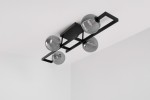 Lampa sufitowa Tores K-5771 w kolorze czarnym i grafitowym, z czterema szklanymi kloszami w kształcie kul, umieszczona na prostej, metalowej konstrukcji. Widok z góry, ukazujący detale kloszy z wypukłym wzorem. Tło jasne, minimalistyczne.