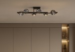 Lampa sufitowa Tores w kolorze czarnym i grafitowym, z sześcioma oprawami na żarówki G9. Ułożona poziomo, z dekoracyjnymi, metalowymi kloszami, umieszczona na gładkim, jasnym suficie. Otoczenie w neutralnych odcieniach.