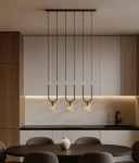 Lampa wisząca Goldi 3xG9 w kolorze czarnym z bursztynowymi kloszami, zawieszona na długich linkach z metalowymi detalami. Widoczna w nowoczesnej kuchni nad okrągłym stołem, z minimalistycznym tłem w odcieniach bieli i drewna.